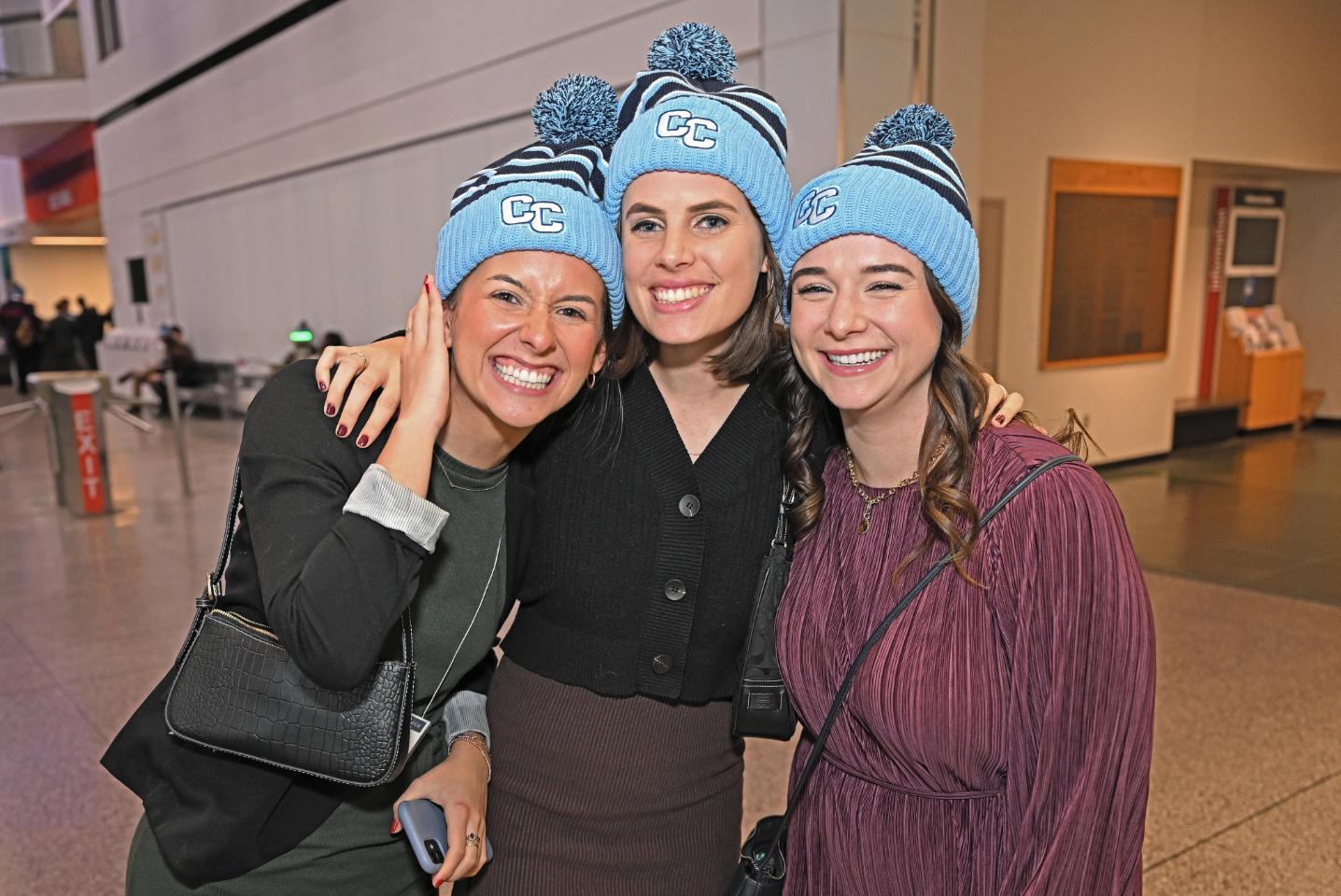 Alumni pose in CC hats at the 2023 Boston Holiday Party