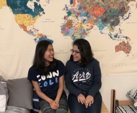 Samirah and her roommate sitting side-by-side giggling on the couch