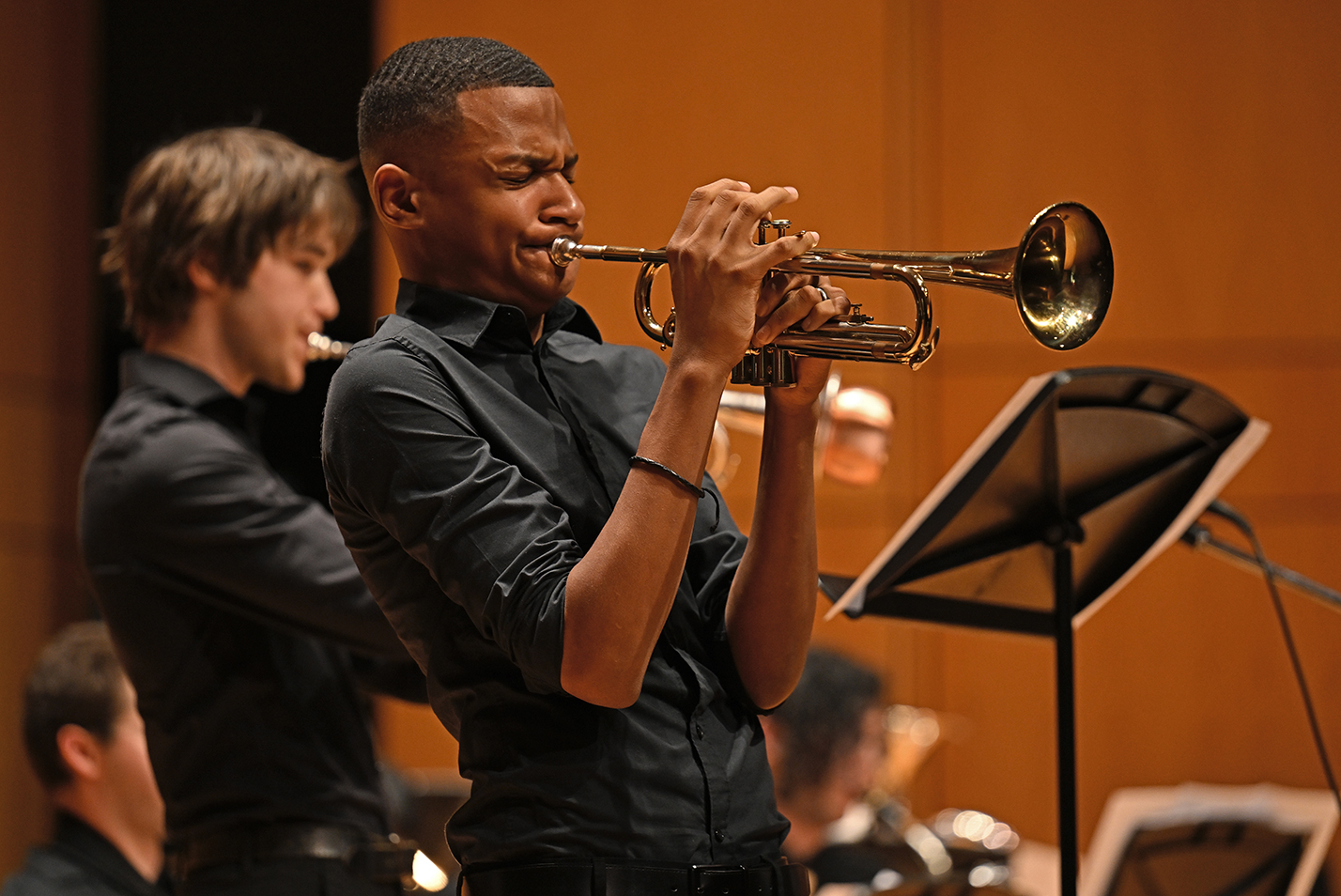 A trumpet player solos on stage with a wind ensemble.