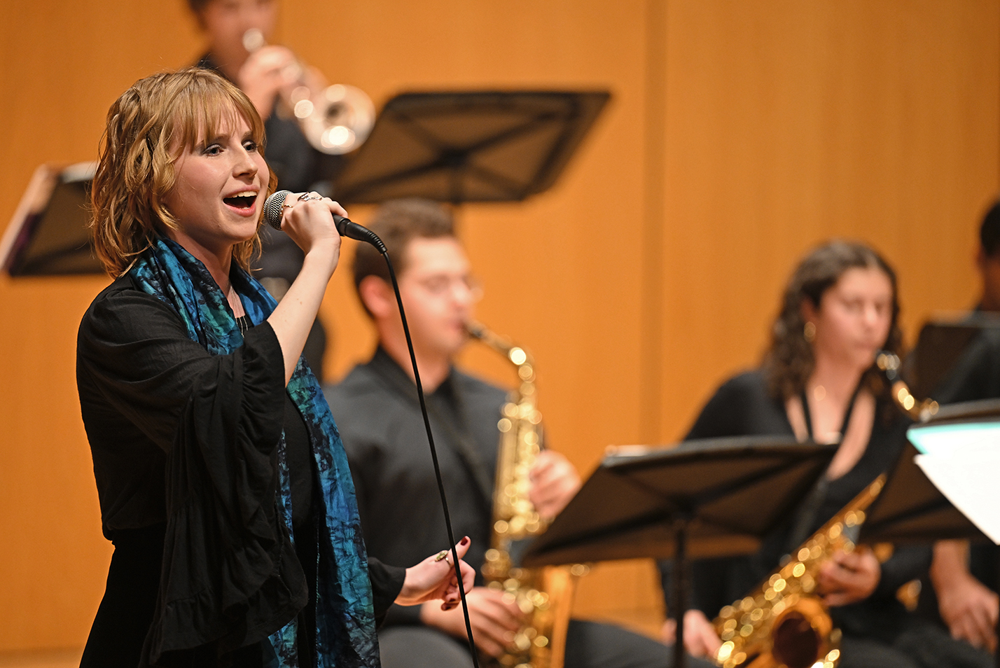 A student sings accompanied by a wind ensemble.